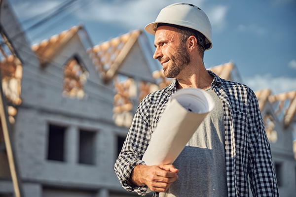 frohlicher-architekt-der-stolz-aussieht-wahrend-er-einen-bauplan-tragt